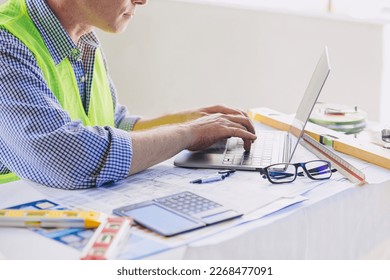 Construction engineer builder working at desk typing on laptop computer. People using mobility 5G Internet wireless connection.