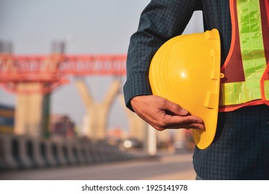 Construction Engineer Holding Yellow Hat Safety Hard Hat On Road Construction Background