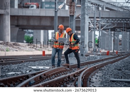 Construction engineer inspecting railway track industrial documents in hand while examining rail structure closely construction, safety and professional project management transportation development.