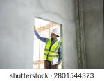 Construction engineer inspecting wall quality inside an unfinished building.