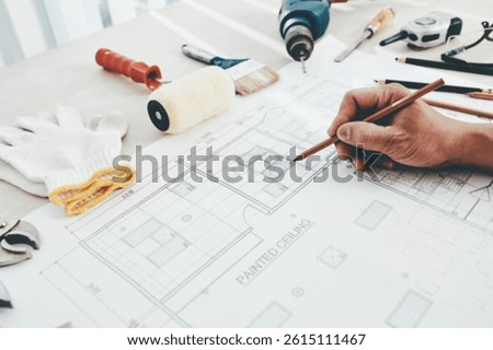 Construction engineer making final corrections in building blueprint or checking size of every detail