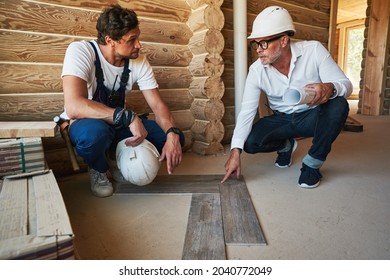 Construction engineer telling builder how to lay parquetry