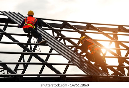 Construction engineer wear safety uniform using an electric drill and screw tools to fasten down metal roofing work for roof industrial concept with copy space