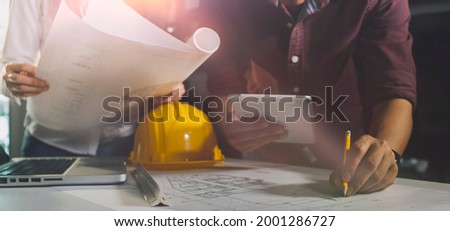 Construction engineer working at blueprint to build large commercial buildings in office. Engineering tools and construction concept.