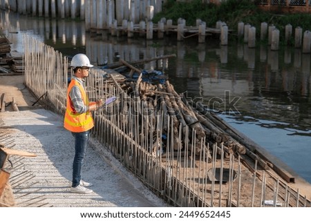 Construction engineer working on a bridge construction site over a river,Civil engineer supervising work,Foreman inspects work at a construction site