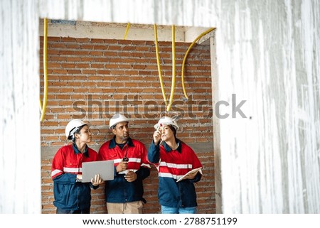 Construction engineers inspecting electrical wiring and communication systems during site walkthrough. Team reviewing installation quality, project compliance, and technical specifications for building infrastructure.