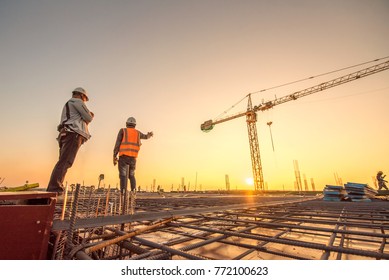 Construction engineers supervising progress construction project stand new concrete floor top roof   crane background