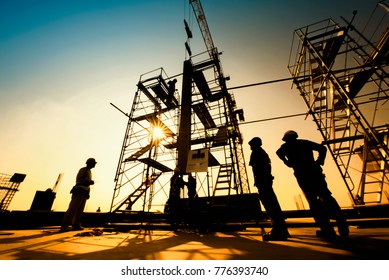 Construction engineers supervising progress of construction project stand on new concrete floor top roof and crane background - Shutterstock ID 776393740