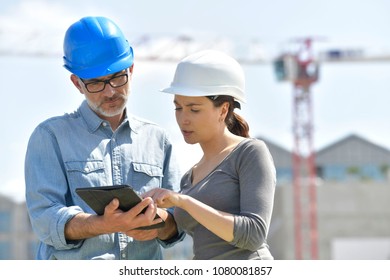 Construction engineers using tablet on building site