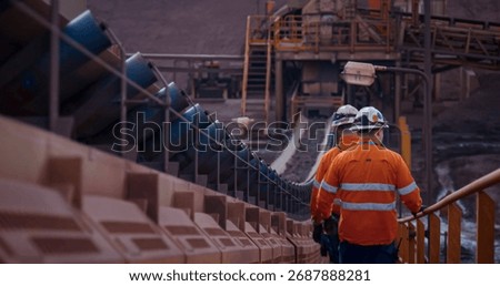 Construction engineers walking alongside material conveyor belts at a mineral processing plant