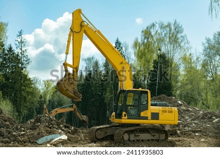 Construction equipment digs ground. Excavated soil. Bucket digs mound. Details of construction of road.