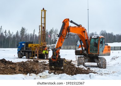 Construction equipment: excavator, drilling machine, on the construction site in winter. Engineering surveys and communications