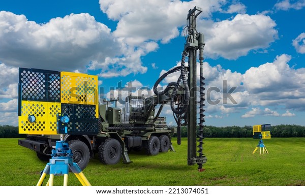 Construction equipment. Machine is drilling well\
in middle green lawn. Geodetic instruments are located on grass.\
Modern geodetic instruments on tripods. Drilling water wells. Well\
drilling process