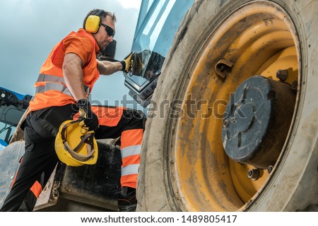 Construction Equipment Operator. Caucasian Industrial Worker in His 30s and Heavy Duty Machinery.