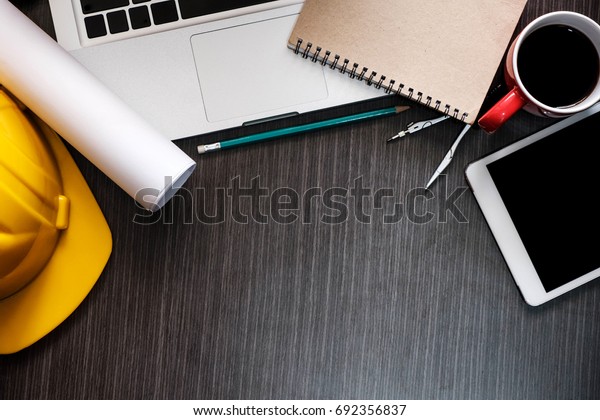 Construction equipment. Repair work. Drawings\
for building Architectural project, blueprint rolls and laptop\
tablet pancil and divider compass on table. Engineering tools\
concept. Copy\
space.\
