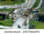 Construction equipment at roadworks site. Reconstruction of damaged road bridge destroyed by river after flood water washed away asphalt. Rebuilding of ruined transportation infrastructure