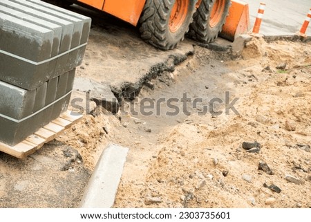 Construction of a footpath. Laying granite tiles on sandy ground and replacing sewer hatches. Improvement of urban areas and renewal of infrastructure