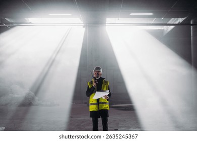 Construction foreman giving instructions over radio during building inspection.