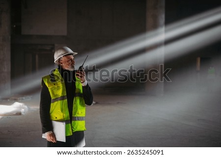 Construction foreman giving instructions over radio during building inspection.