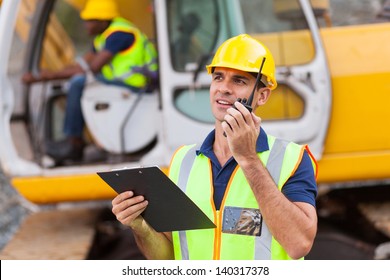 construction foreman talking on walkie-talkie holding clipboard - Powered by Shutterstock