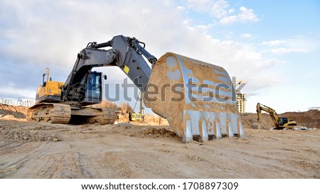 Construction of foundation excavator works in sand pit. Groundworks, site levelling, construction of reinforced ground beams on piled foundations at construction site. Earth-moving heavy equipment 