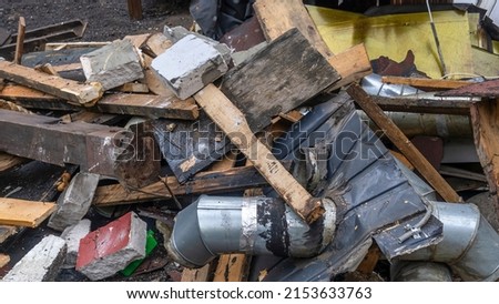 Construction garbage is piled up at site after building repair. Trash heap. Pile of home rubbish thrown after renovation. Waste and timber dumped. Cleaning and sorting garbage after demolition jobs.
