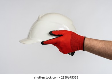 Construction Helmet In The Hands Of A Worker. Symbol Of Construction, Repair. Protective Uniform. Man In Work Gloves Holds A Helmet In His Hands. Safety Hard Hat Isolated On White 