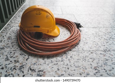 Construction Helmet Lying On A Power Chord And The Floor.