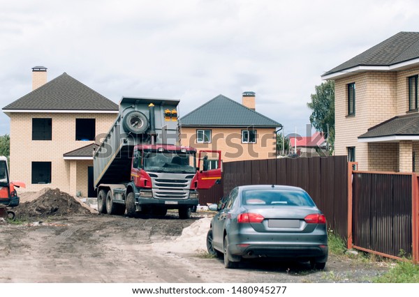 Construction of houses in the private sector.\
A truck unloads construction\
materials\
