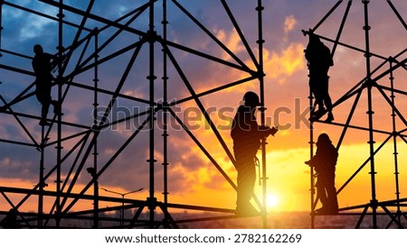 Construction industry and scaffolding assembly. Workers install metal framework at construction site during sunset with industrial safety equipment.