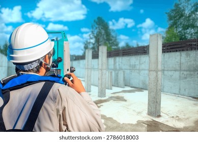 Construction industry. Survey engineer performs geodetic inspection of concrete foundation and columns at building site using total station equipment