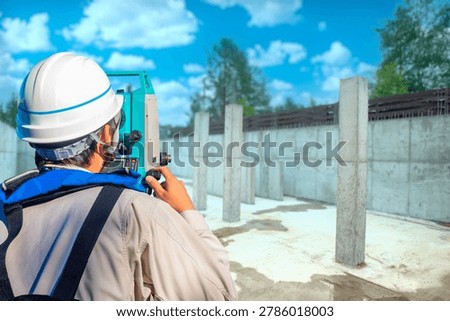 Construction industry. Survey engineer performs geodetic inspection of concrete foundation and columns at building site using total station equipment