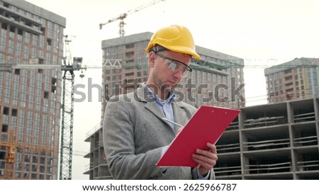 Construction inspector making notes during inspection of building objects