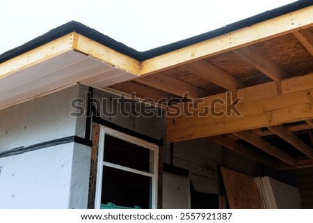 Construction are installing roofing materials on house, focusing on eave detailing improvements.