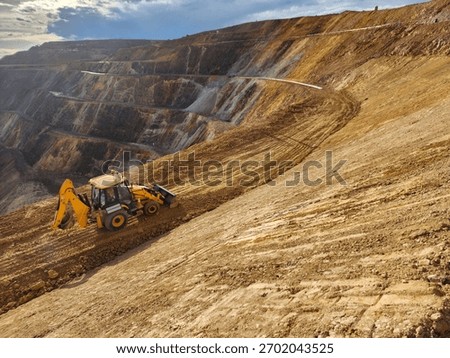 Construction machinery in the process of profiling a bench in an open-pit mine