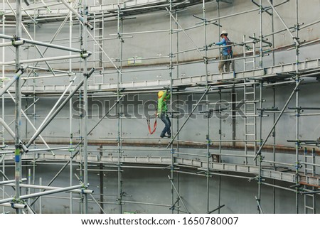 Construction male workers tank oil installing scaffolding in side tank confined spec