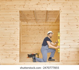 Construction man, builder man construct new wooden home, tiny house style. Spirit level, screw, tool bag and charged drill. Wood shelter style.