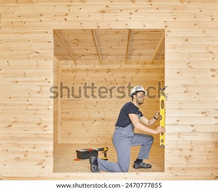 Construction man, builder man construct new wooden home, tiny house style. Spirit level, screw, tool bag and charged drill. Wood shelter style.