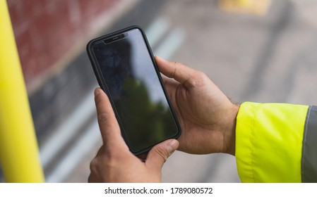 construction man holding a mobile on site. Man pointing on smartphone screen, chatting in social networks, site meeting, social distancing, meeting website and sending sms, text messenger on site. - Powered by Shutterstock