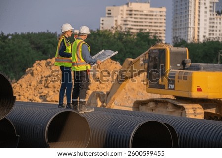 Construction Manager and engineer working construction site blueprint for survey inspection detail of construction with pipe heavy machinery excavator constructed hi-way road background.