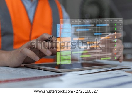 Construction manager using digital tablet to monitor Gantt chart project timeline. Concept for smart construction planning, scheduling, workflow management, and digital project control.