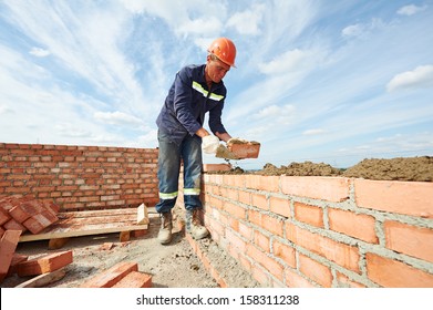 Construction Mason Worker Bricklayer Installing Red Brick With Trowel Putty Knife Outdoors