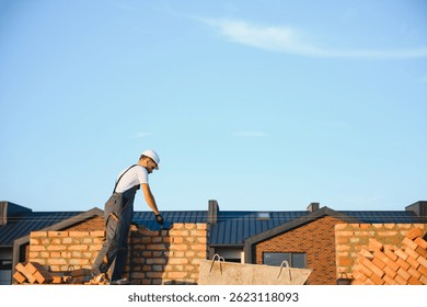construction mason worker bricklayer installing red brick with trowel putty knife outdoors.