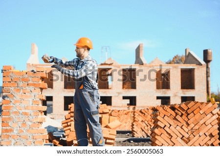 construction mason worker bricklayer installing red brick with trowel putty knife outdoors.