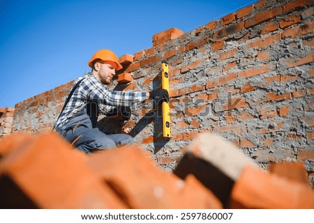 construction mason worker bricklayer installing red brick with trowel putty knife outdoors.