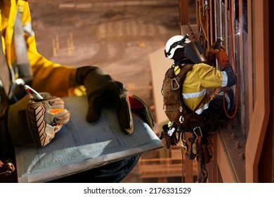 Construction miner supervisor wearing safety glove signing working at height working permit on open field job site prior to starting high risk rope access working at height construction mine site  - Shutterstock ID 2176331529
