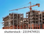 Construction of modern high-rise buildings. Construction of buildings using in-situ concrete, reinforced concrete slabs and brick blocks. Work on a construction site with a crane.