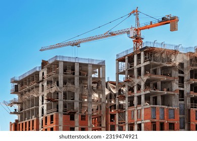 Construction of modern high-rise buildings. Construction of buildings using in-situ concrete, reinforced concrete slabs and brick blocks. Work on a construction site with a crane.