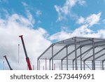 Construction of modern steel structure under blue sky with cranes working on site