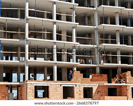 Construction of a multi-storey building. A crane is working. Builders are building a house.